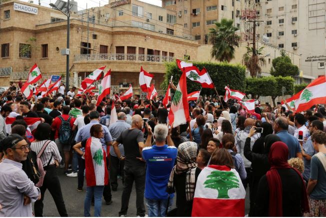 متظاهرون يحملون الأعلام اللبنانية في مظاهرة ضد الحكومة في لبنان يوم الأربعاء. تصوير: عزيز طاهر - رويترز.